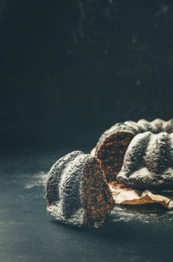 Baharatlı çikolatalı pasta ve kurutulmuş meyve ve çikolata parçacıkları, üzerine pudra şekeri serpiştirilmiş. Aromatik ev yapımı kekler. Kutlama. Ev yapımı kekler, tatlı pasta. Pasta masada. tatlı.