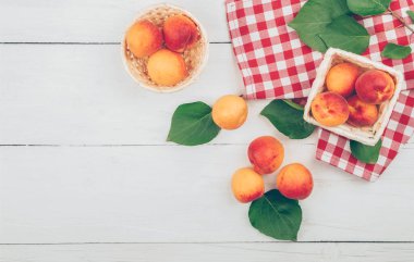 Tahta arka planda yeşil yapraklı olgun kayısılar. Taze çiftlik kayısı hasadı. Lezzetli kayısılar. Üst Manzara. Düz yatıyordu.