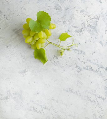 Yeşil asmanın üst görüntüsü, ve eski gri taş masa zemininde olgun üzüm. Şarap dükkanı şaraphanesi ya da şarap tatma konsepti. Üzüm. Üzüm yapraklı bir demet beyaz üzüm. Pankart. Boşluğu kopyala