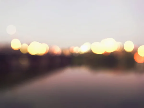 Blurred evening background. City lights on sunset. Night life. Blurry city lights. City night. Modern cityscape, Blurred night street. River with lights. Lanterns are reflected in the water