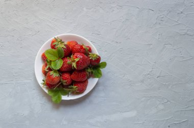 Çilek arka planı. Tabakta taze çilek. Yemek arkaplanı. Taze biçilmiş çilek, en iyi manzara. Olgun organik tatlı çilek. En tepeden yaz meyvesi. Vitaminli lezzetli vejetaryen atıştırmalığı..