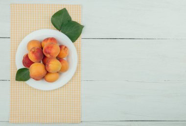 Kırsal arka planda olgun kayısılar. Ahşap arka planda yaprakları olan kayısılar. Metin için kopyalama alanı olan olgun kayısılar. Çeşitli taze yaz meyveleri. Ahşap bir masada kayısılar. Üst görünüm.