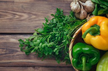 Fresh sweet peppers and herbs on a wooden table. View from above. Flat lay. Healthy food and lifestyle concept. Gardening. Parsley, dill, basil, celery, onion, tomato and celery. Salad. Summer, autumn