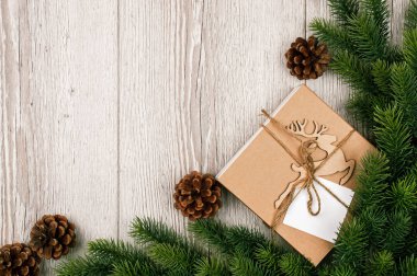 İçinde geyik olan yeni yıl hediyesi kutusu, tahta bir arka planda ağaç dalı. Metin için yeri olan pankart. Kırsal arka plan. Noel ağacı dalları olan eski ahşap döşeme. Düz. Üst yaşam