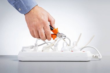 Enerji tasarrufu kavramı. Enerji tasarrufu için elektrik kablolarını kesen tel kesicili bir erkek el..