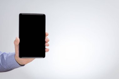 Siyah tablet bilgisayarı gri arka planda erkek elinde..