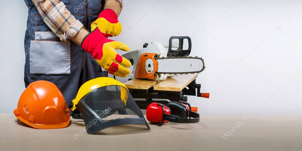 Worker puts on gloves, protective equipment for occupational safety  work.  lumberjack with protective equipment. Banner.