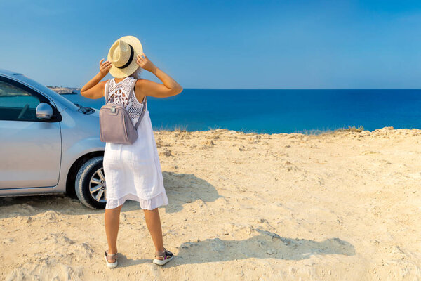 Beautiful stylish adult, mature woman  travels by car, with a hat and with a card in her hands, summer travel, freedom, transport for rent, new impressions and adventure, freedom.