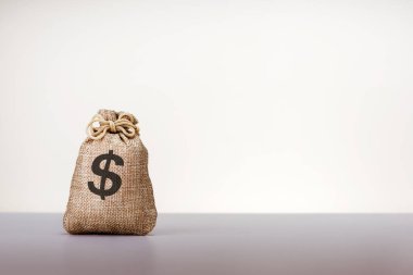 Gri arka planda dolar işareti ve fotokopi alanı olan çuval bezi. Para, bankacılık kavramı.