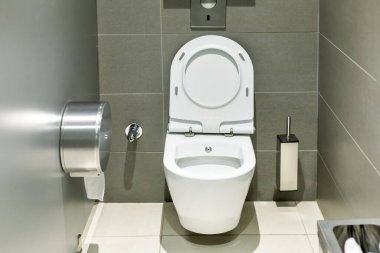 Duvarında gri fayanslar olan modern umumi tuvalet..