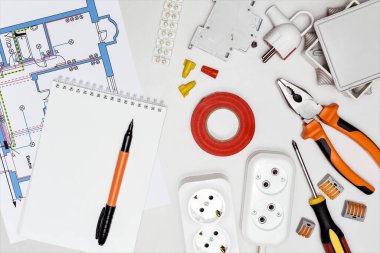Elektrik teçhizatı, araçlar, şemalar ve defter masanın üstünde, üst görünüm.