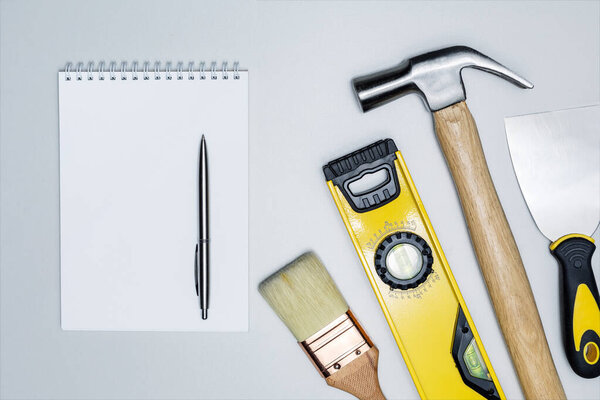 Different construction tools and notebook on grey surface. Top view. Writing work plan. DIY concept.