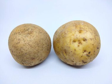 Beyaz arka planda derisi temizlenmemiş 2 parça çiğ organik patates.