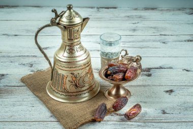 Ramadan concept: Dates, zam zam water in copper jugs and glasses and on white table. clipart