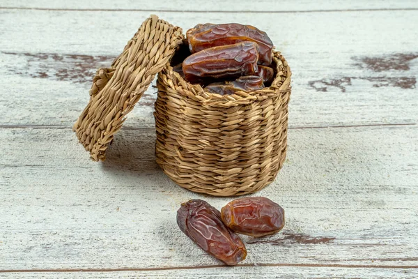 close up picture of dates palm fruit in cup on wooden table background. Dates palm fruit dry is snack healthy.