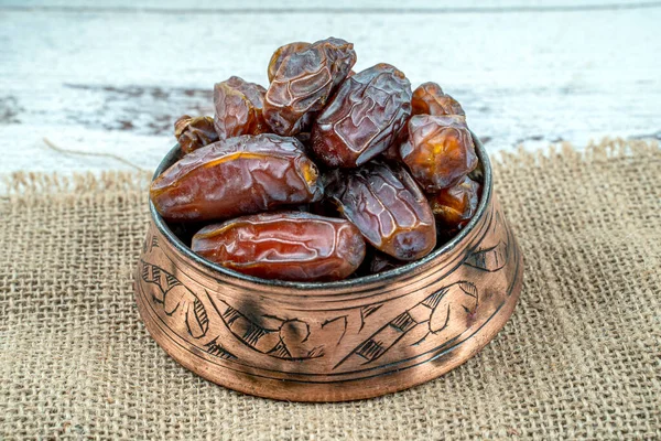 close up picture of dates palm fruit in cup on wooden table background. Dates palm fruit dry is snack healthy.