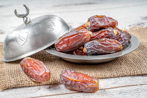 close up picture of dates palm fruit in cup on wooden table background. Dates palm fruit dry is snack healthy.