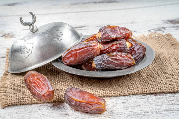 close up picture of dates palm fruit in cup on wooden table background. Dates palm fruit dry is snack healthy.