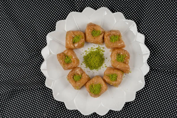 Tahta tepside fındıklı fındıklı fındıklı sütlü baklava, Türk baklavası, yerel adı Sutlu nuriye baklava veya sütlü baklava ile servis edilir.