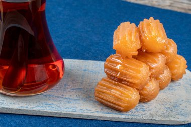 Geleneksel Türk tatlı tulumbası, ahşap bir tabakta çay ile servis edilen tulumba tatlisi.