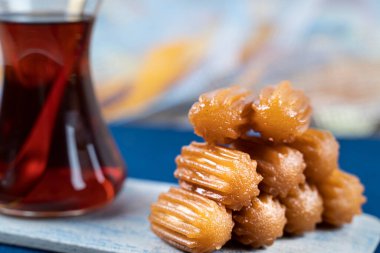 Geleneksel Türk tatlı tulumbası, mermer bir tabakta çay ile servis edilen tuumba tatlisi.