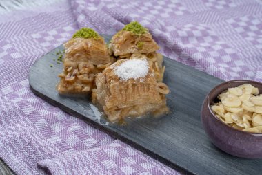 Tahta tepside fındıklı fındıklı fındıklı sütlü baklava, Türk baklavası, yerel adı Sutlu nuriye baklava veya sütlü baklava ile servis edilir.