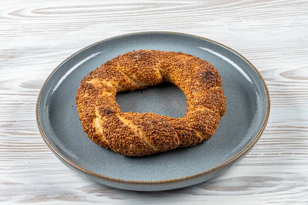 Simit ya da gevrek, beyaz ahşap arka planda geleneksel Türk hamur işi yiyeceği. Türk sokak yemekleri dairesel ekmek, susamlı simit.