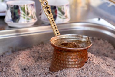 Sıcak kumda geleneksel Türk kahvesi hazırlandı. Sıcak altın kumda Türk kahvesi yapmak için seçici bir odak. Kahve hazırlama konsepti. Alternatif ve eski kahve demleme metodu.