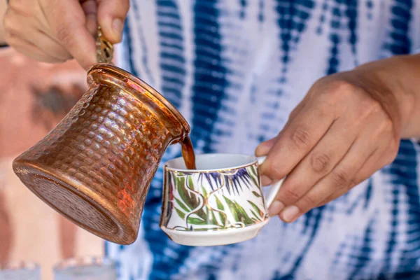 Traditional turkish coffee in cezve prepared on hot sand. Selective focus making turkish coffee on hot golden sand. Coffee preparation concept. Alternative and old method of brewing coffee.