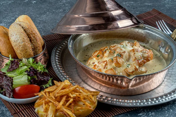 Sarımsaklı kremalı tavuk fileto, kalın soslu koyu arkaplanda dökme tava. Salata ve patatesle servis edilen lezzetli ev yapımı yemekler.
