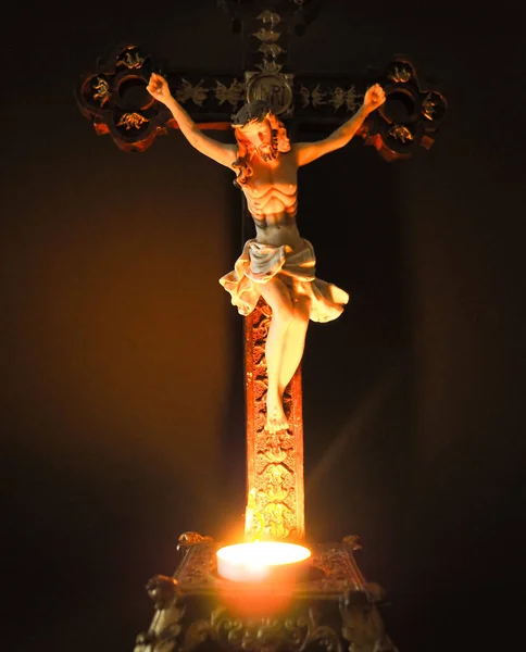 Jesus Christ on the cross with burning candle, dark background