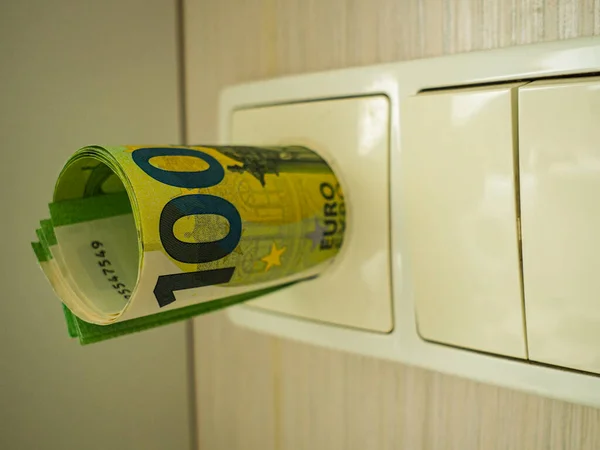 Elektrik prizine sıkışmış 100 avroluk banknot, yükselen enerji fiyatları kavramı