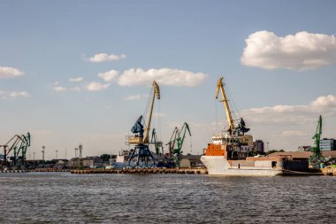 Deniz kargo limanı. Uzakta turnalar var. Mavi deniz, yaz günü