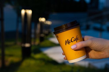 McDonalds 'ın sarı bardağı bir kızın elinde fenerlerin arka planında.