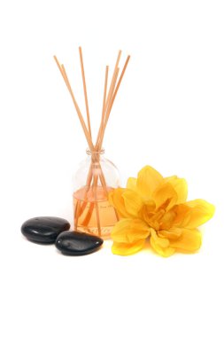 Masaj taşları, parfüm çubukları ve beyaz arka planda çiçekler.