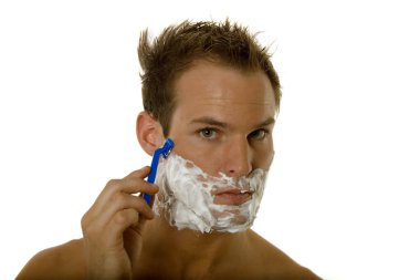 Genç bir erkek tıraş olurken sakalını tıraş ediyor.