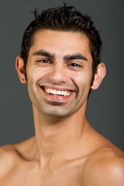 Genç yakışıklı, çok kültürlü adam gülümsüyor.