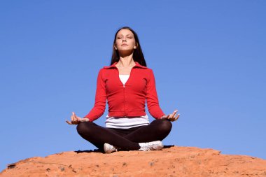 Kızıl kayalarda meditasyon yapan genç bir kadın.