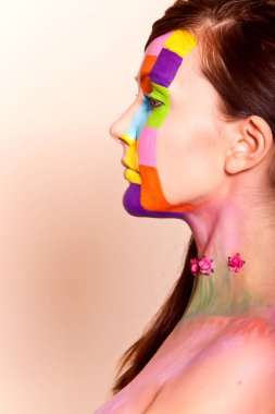 Uzun saçlı, esmer, renkli makyajlı bir kız.