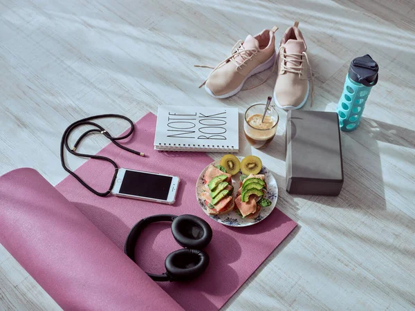From above of healthy toasts and cup of coffee on yoga mat placed on floor before morning training