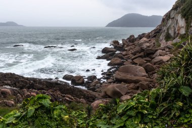Dalgalar kıyıdaki deniz kayalarına vuruyor. Kıyıdaki deniz taşları. Brezilya 'da deniz taşları görünüyor
