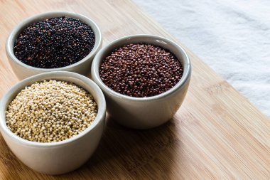 Ahşap arka planda kırmızı, siyah ve beyaz kinoa tohumları. Vejetaryen yemeği.