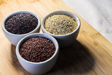 Ahşap arka planda kırmızı, siyah ve beyaz kinoa tohumları. Vejetaryen yemeği.