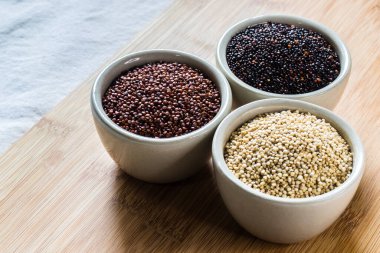 Ahşap arka planda kırmızı, siyah ve beyaz kinoa tohumları. Vejetaryen yemeği.