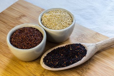 Ahşap arka planda kırmızı, siyah ve beyaz kinoa tohumları. Vejetaryen yemeği.
