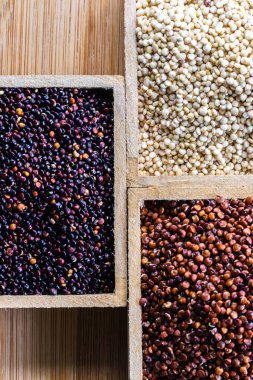 Ahşap arka planda kırmızı, siyah ve beyaz kinoa tohumları. Vejetaryen yemeği.