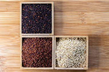 Ahşap arka planda kırmızı, siyah ve beyaz kinoa tohumları. Vejetaryen yemeği.