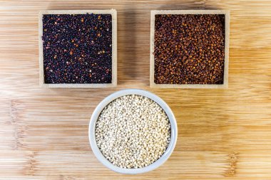 Ahşap arka planda kırmızı, siyah ve beyaz kinoa tohumları. Vejetaryen yemeği.