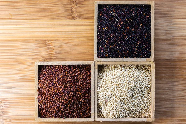 Ahşap arka planda kırmızı, siyah ve beyaz kinoa tohumları. Vejetaryen yemeği.