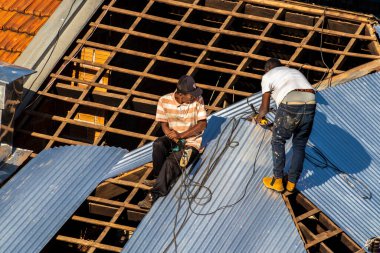 Marilia, Sao Paulo, Brezilya, 29 Temmuz 2022. Marilia 'nın merkezindeki ticari bir noktanın çatısını yenilemek için bir eve metal çarşaf döşeyen bir işçinin üst görüntüsü.